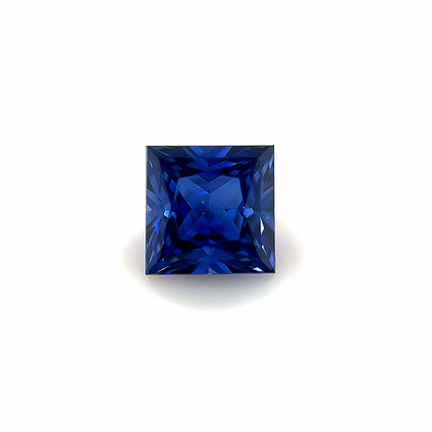 A 6mm Exceptional Square Princess Lab Created Sapphire with a deep blue hue, showcased against a plain white background.