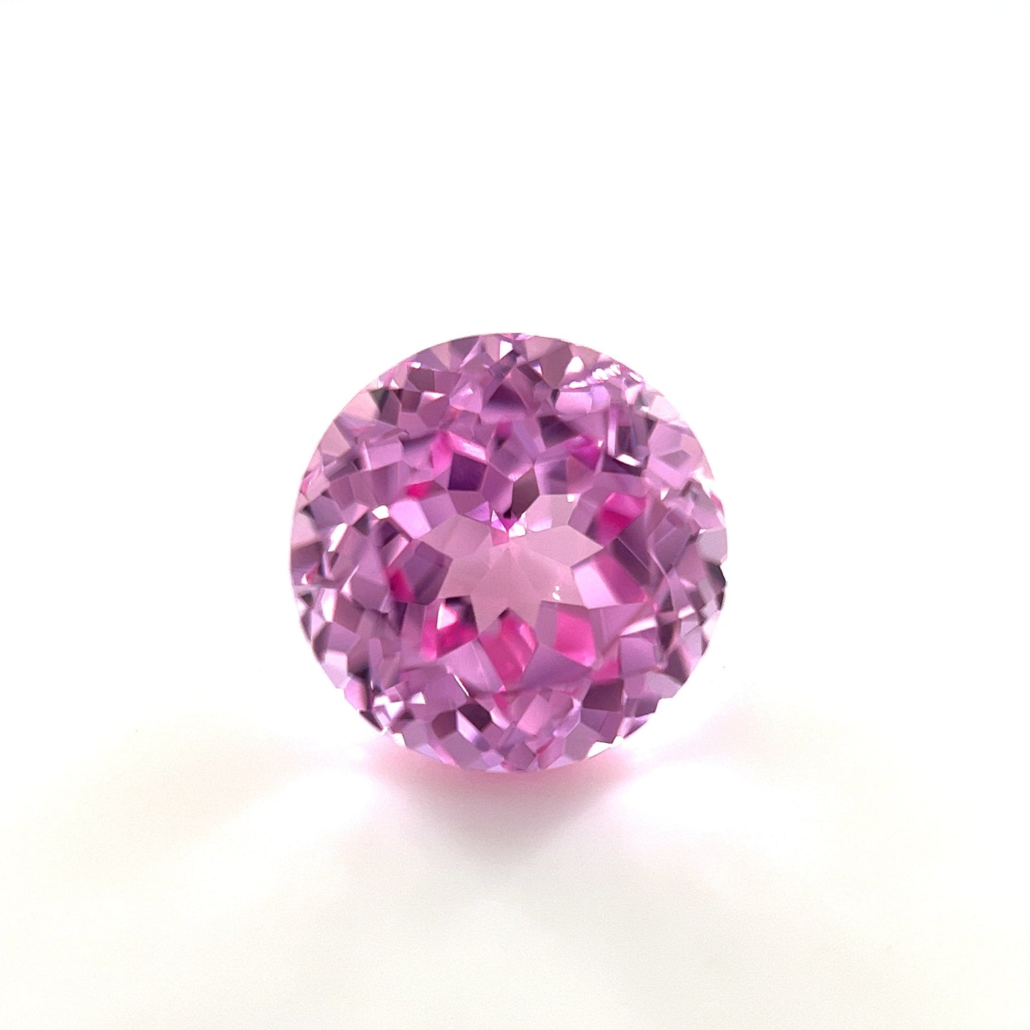 A 6mm Exceptional Round Lab Created Medium Pink Sapphire with a faceted, sparkling surface is shown against a plain white background.