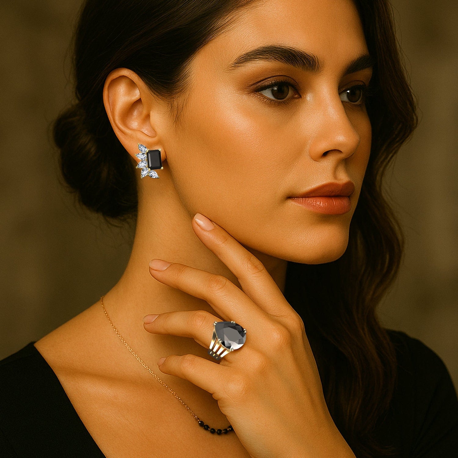 Close-up of a woman wearing black diamond earrings and a ring with a neutral background
