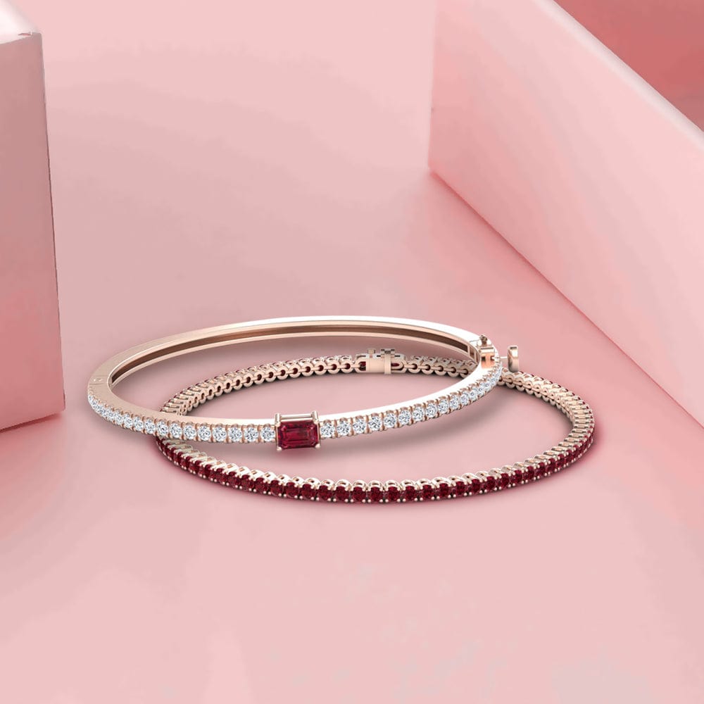 Two bracelets with red and clear stones on a pink background