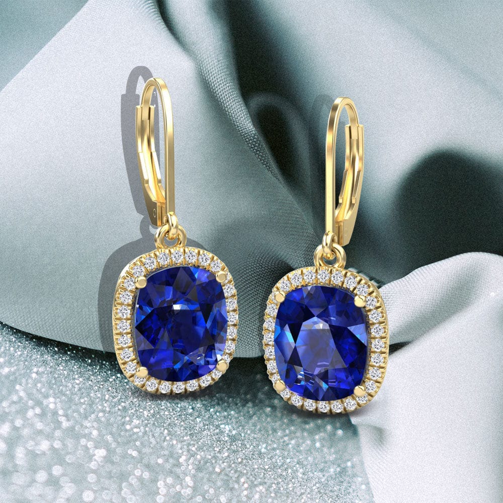 Gold earrings with blue sapphire gemstones on a soft fabric background