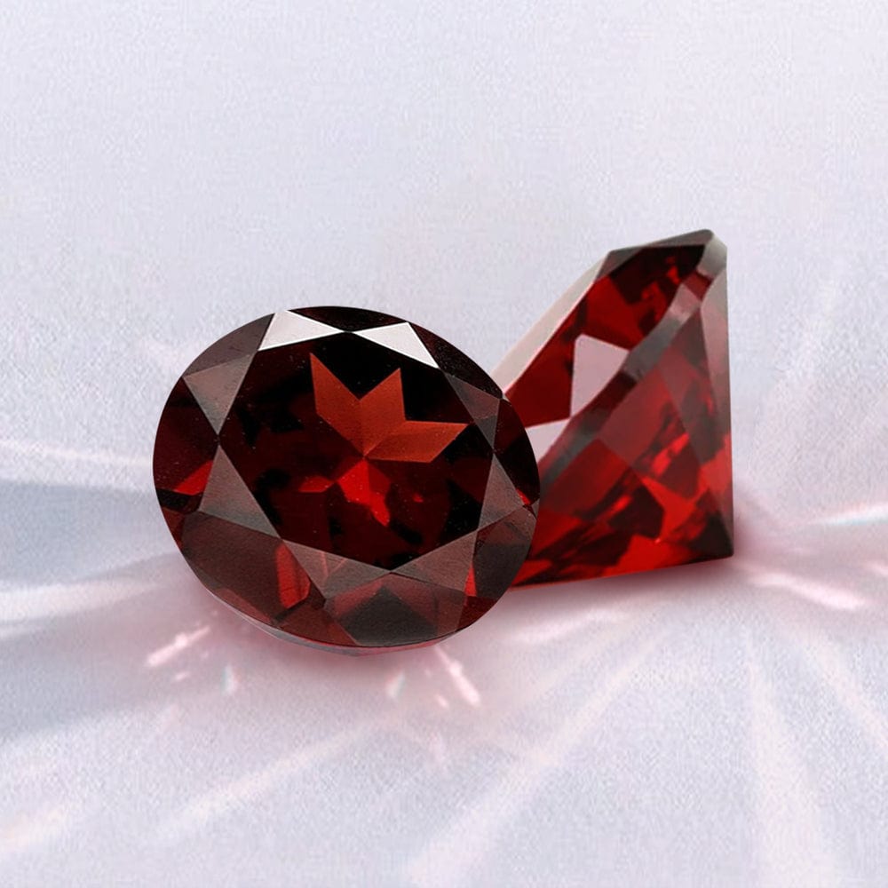 Two red garnet gemstones on a white background