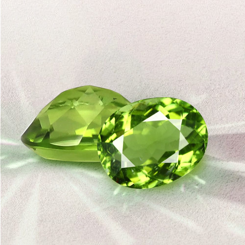 Two green peridot gemstones on a light gray background