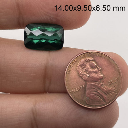 A hand holds a 6.70 carat cushion checker green tourmaline (14.0 x 9.5 mm) next to a 2020 US penny for size comparison; gem dimensions appear in the top right corner.
