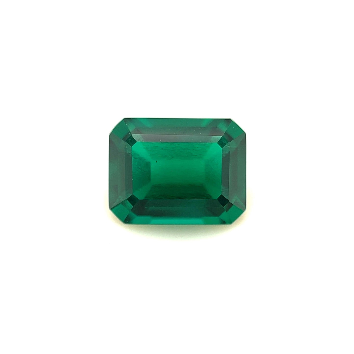 The 9x7 Exceptional Emerald Color Lab Created Emerald is a rectangular, emerald-cut green gemstone with beveled edges, shown against a plain white background.