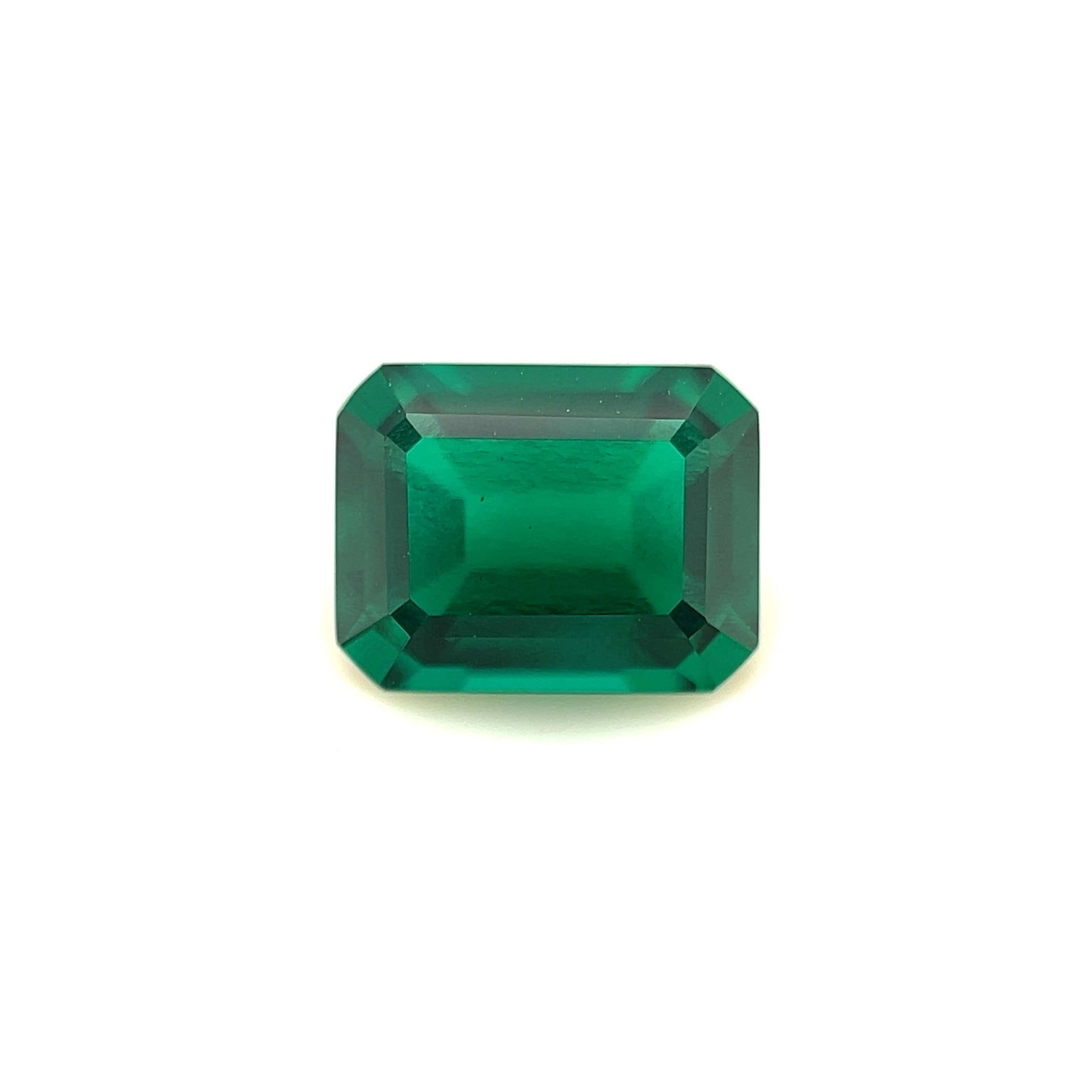 The 9x7 Exceptional Emerald Color Lab Created Emerald is a rectangular, emerald-cut green gemstone with beveled edges, shown against a plain white background.