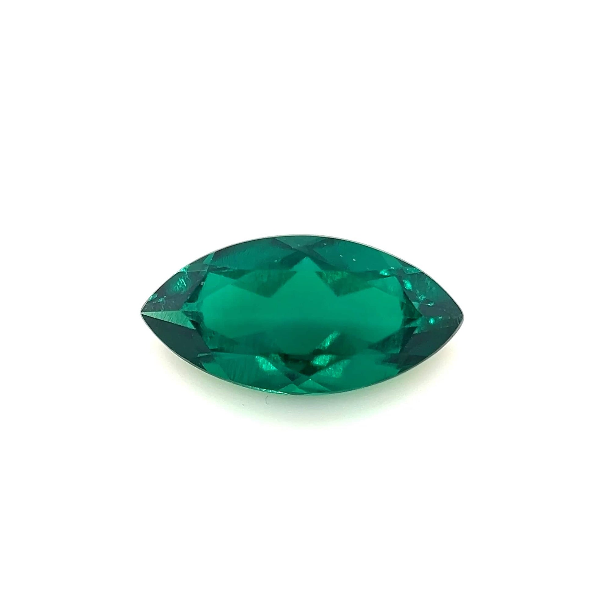 The 12.0x6.0 Exceptional Marquise Color Lab Created Emerald, shown on a plain white background, features sharp pointed ends and faceted surfaces that reflect light brilliantly.