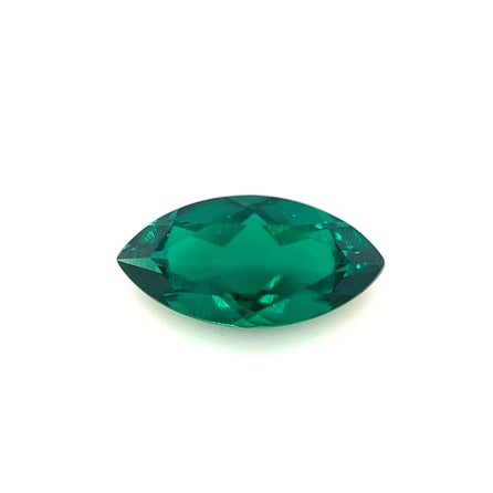 The 12.0x6.0 Exceptional Marquise Color Lab Created Emerald, shown on a plain white background, features sharp pointed ends and faceted surfaces that reflect light brilliantly.