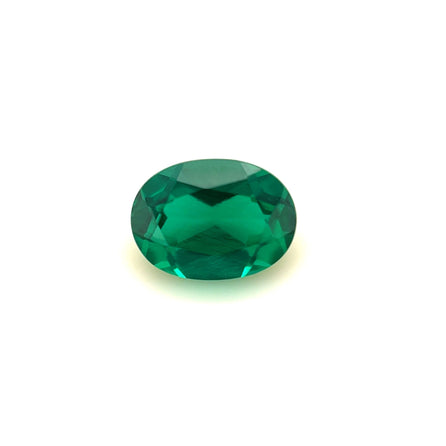 The 7x5 Exceptional Oval Zambian Color Lab Created Emerald, expertly faceted and vibrant green, is showcased on a plain white background.