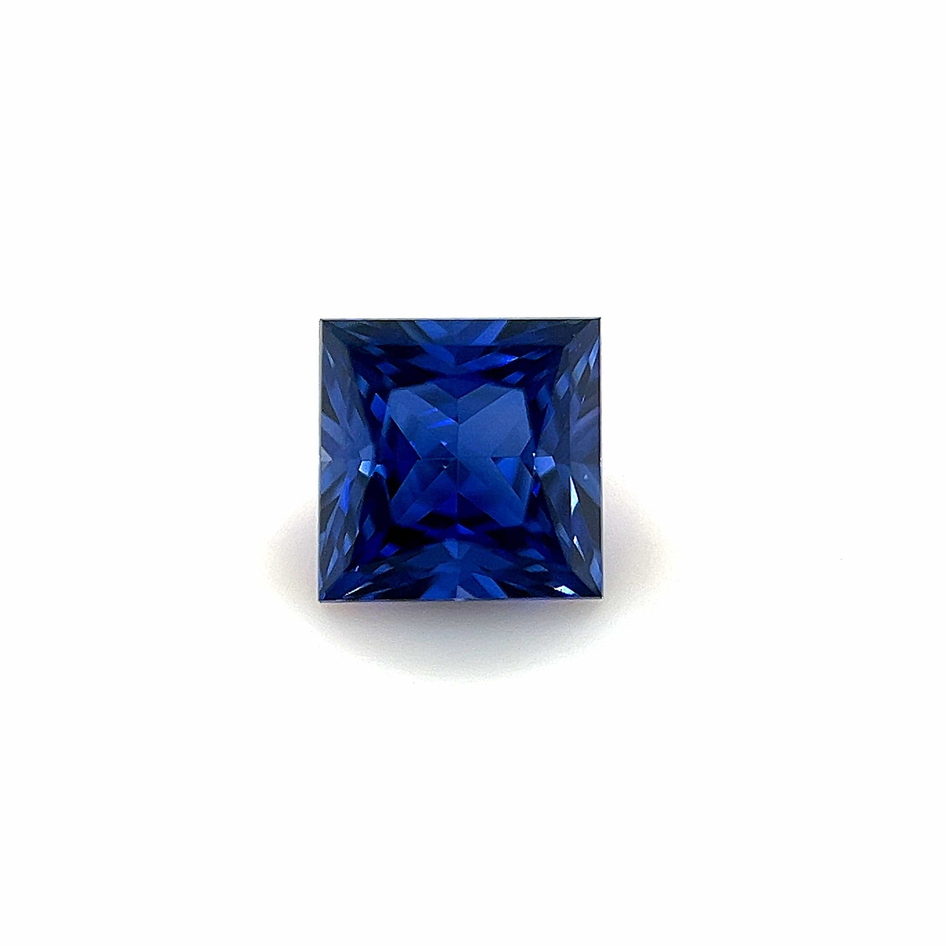 A 6mm Exceptional Square Princess Lab Created Sapphire with a deep blue hue, showcased against a plain white background.