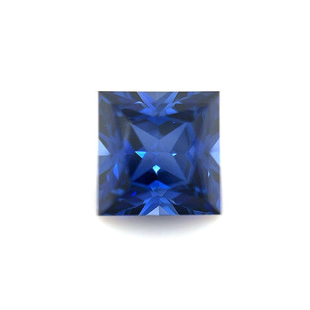 A 7mm Exceptional Square Princess Lab Created Blue Sapphire with intricate facets and deep blue color is displayed on a plain white background.