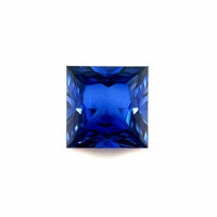 The 8mm Exceptional Square Princess Created Blue Sapphire features angled facets that reflect light, displaying a vibrant, deep blue hue against a white background.