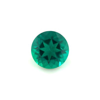 A 6.5mm Exceptional Round Zambian Color Lab Created Emerald, faceted with a star-shaped center pattern, displayed on a plain white background.