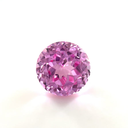 A 6mm Exceptional Round Lab Created Medium Pink Sapphire with a faceted, sparkling surface is shown against a plain white background.