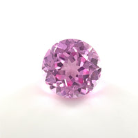 A 9mm Exceptional Round Lab Created Medium Pink Sapphire with faceted cuts is displayed on a plain white background, highlighting its sparkling medium pink tones and reflective surfaces.