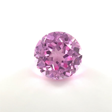 A 9mm Exceptional Round Lab Created Medium Pink Sapphire with faceted cuts is displayed on a plain white background, highlighting its sparkling medium pink tones and reflective surfaces.