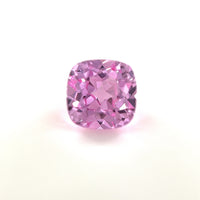 A 6mm Exceptional Cushion Lab Created Medium Pink Sapphire is shown against a white background, highlighting its vibrant color and sparkling clarity.