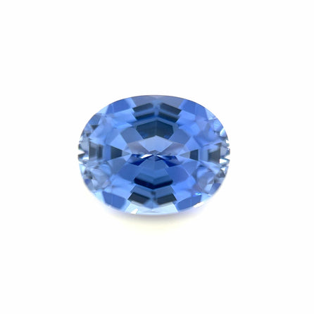 The 9.0x7.0 Exceptional Oval Step Lab Created Light Blue Sapphire features an oval cut and step facets, displaying a vibrant light blue hue set against a plain white background.