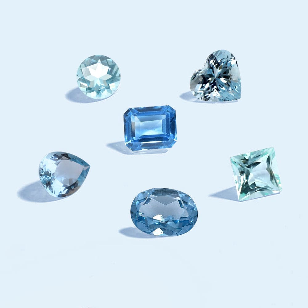 Collection of blue aquamarine gemstones on a light blue background