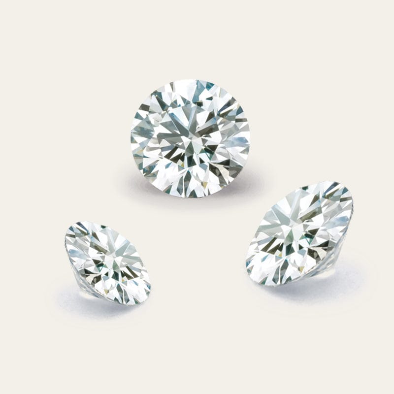 Three round diamonds of different cuts on a light gray background