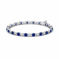 The Lab Grown Blue Sapphire & Diamond Halo Tennis Bracelet - Isabella features round blue sapphires and diamonds set in silver, with gemstones evenly spaced around the band, shown on a white background.