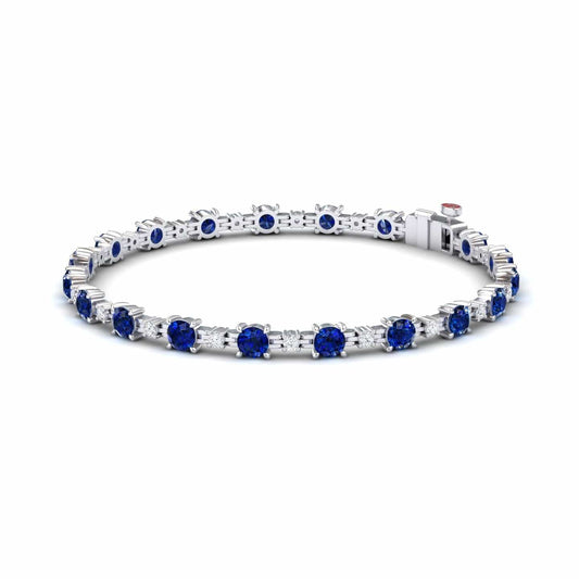The Lab Grown Blue Sapphire & Diamond Halo Tennis Bracelet - Isabella features round blue sapphires and diamonds set in silver, with gemstones evenly spaced around the band, shown on a white background.