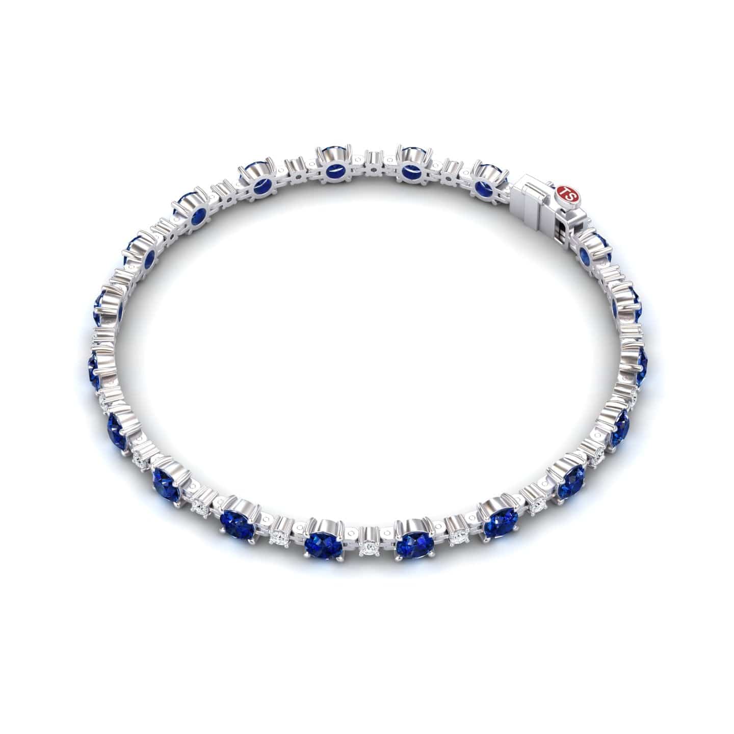 The Lab Grown Blue Sapphire & Diamond Halo Tennis Bracelet - Isabella features evenly spaced blue sapphires, each encircled by sparkling diamonds, beautifully displayed against a white background.
