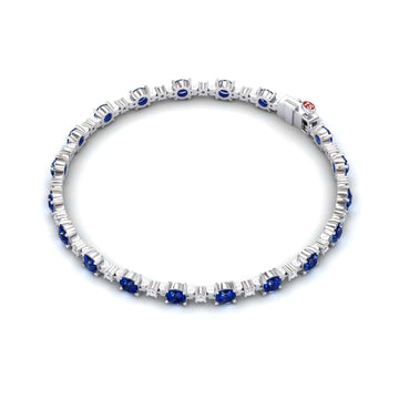 The Lab Grown Blue Sapphire & Diamond Halo Tennis Bracelet - Isabella features evenly spaced blue sapphires, each encircled by sparkling diamonds, beautifully displayed against a white background.