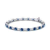 The London Blue Topaz & Diamond Tennis Bracelet - Natalia features round blue gemstones in prong settings, shown on a white background.