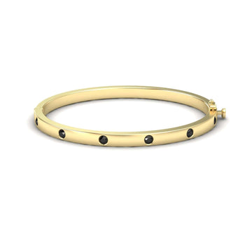 The Black Diamond Bezel-Set Bracelet - Flavia features evenly spaced black gemstones set in gold, displayed against a plain white background.