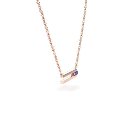 Introducing the Cecilia Tanzanite Bar Necklace: a delicate rose gold chain with a minimalist horizontal bar pendant, accented by a small blue tanzanite gemstone on one side.