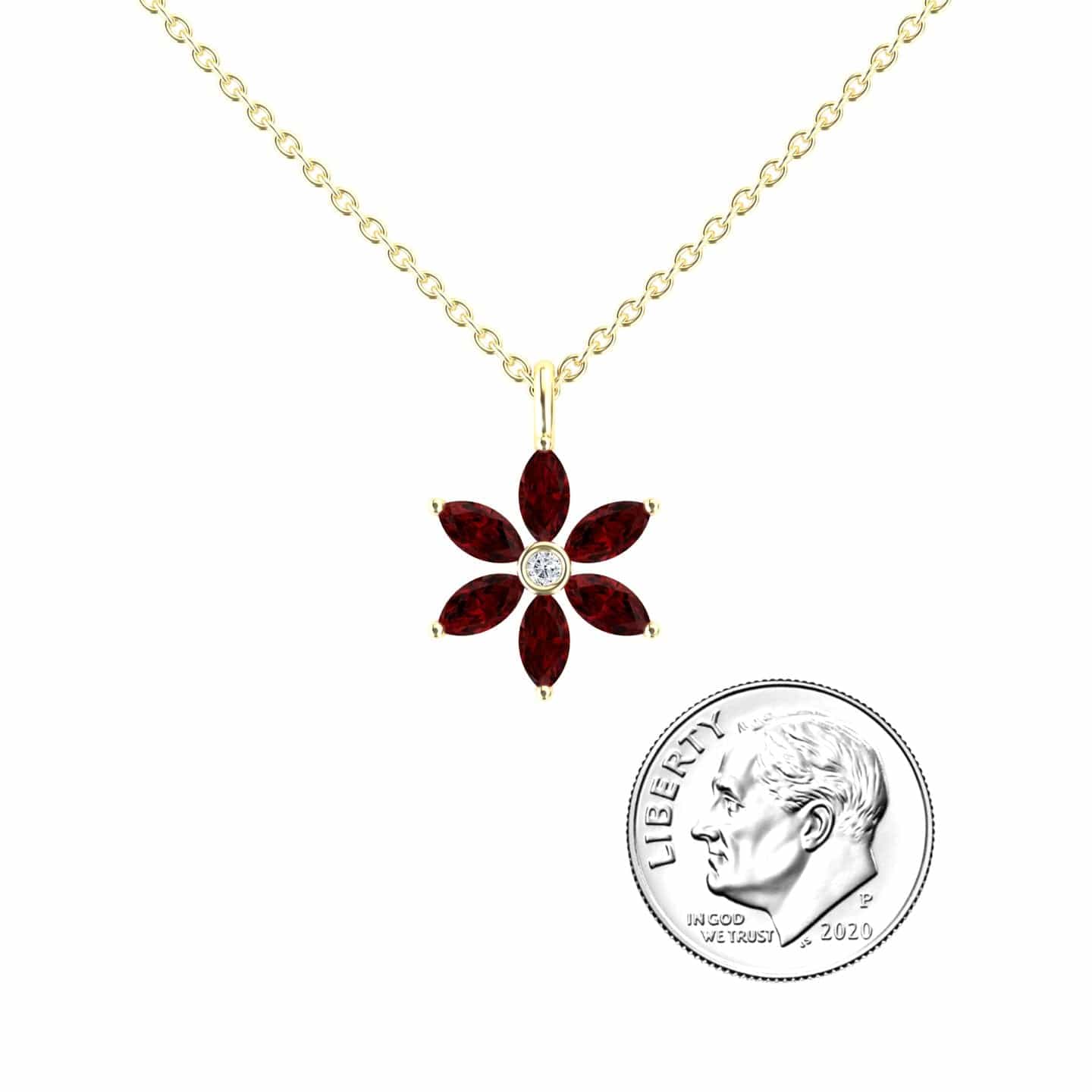 The Lab Grown Ruby & Diamond Floral Necklace - Erin features a gold chain with a flower-shaped pendant of six marquise-cut red stones and a central clear stone, shown beside a 2020 US dime for scale.