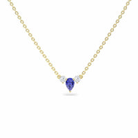 The Tanzanite & Diamond Three-Stone Necklace - Jina showcases a teardrop-shaped blue tanzanite pendant flanked by two round diamonds, all set on a gold chain and displayed against a white background.