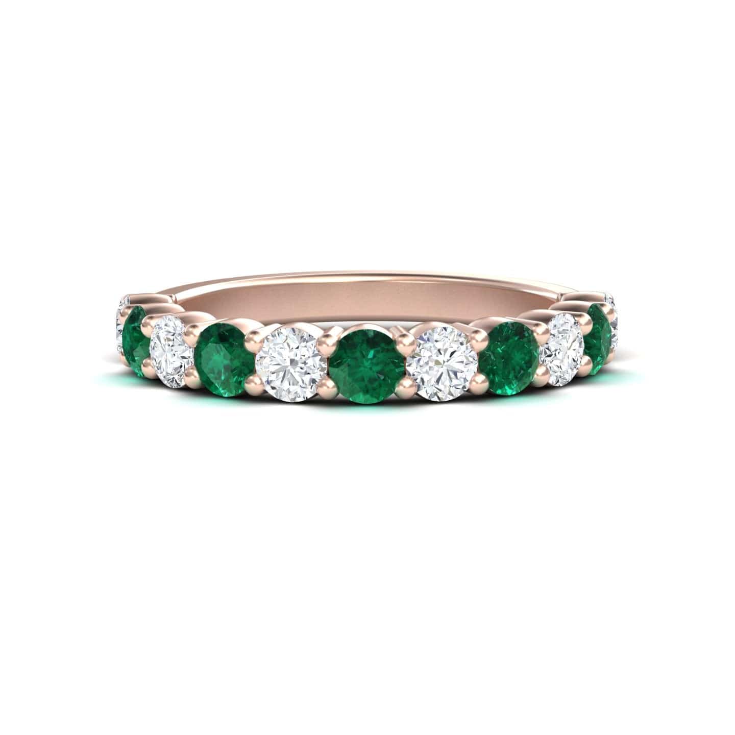 A rose gold half eternity wedding ring with alternating emerald and diamond gemstones.