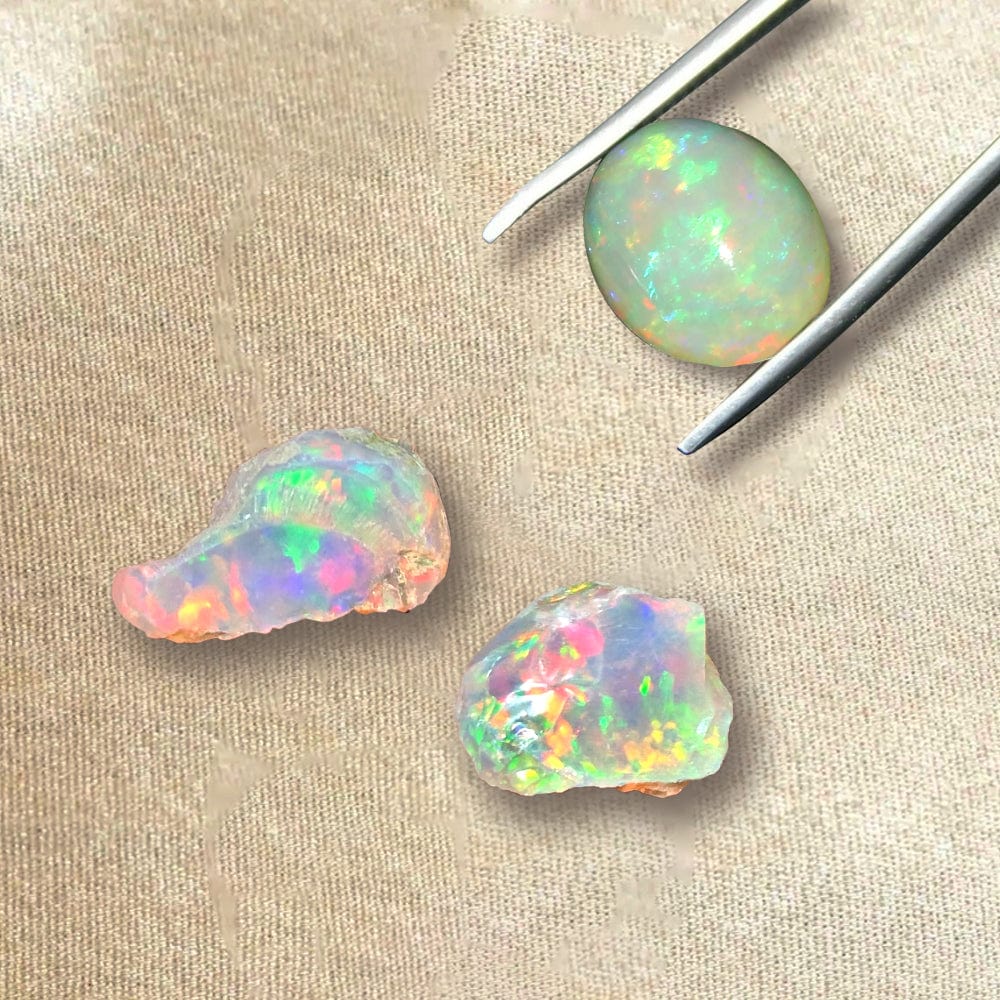 Three pieces of colorful opal stones on a beige surface with tweezers.