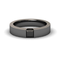 The Black Diamond Solitaire Mens Band - Xiuling features a sleek, modern design with a flat, polished black band and a square black gemstone set flush at the center.