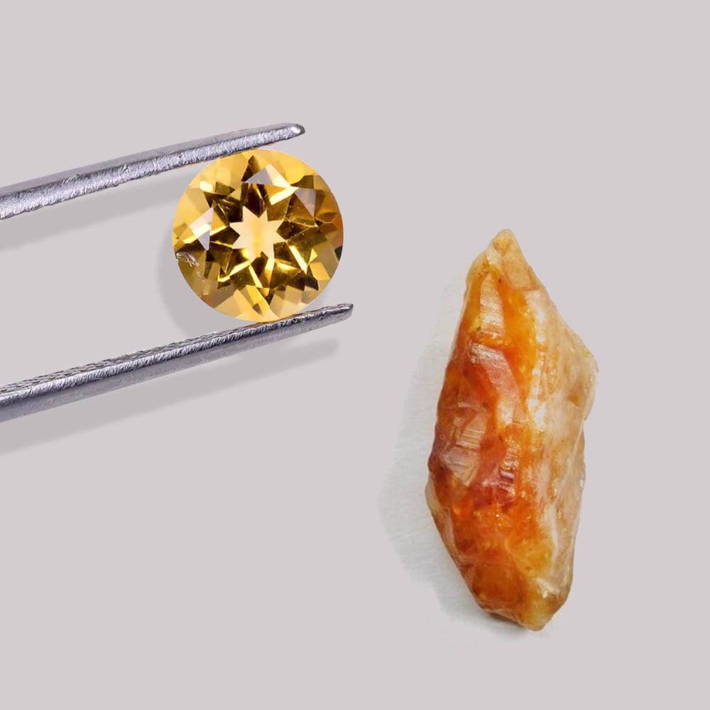 Round cut yellow citrine gemstone held by tweezers next to its rough, uncut counterpart on a light gray background.