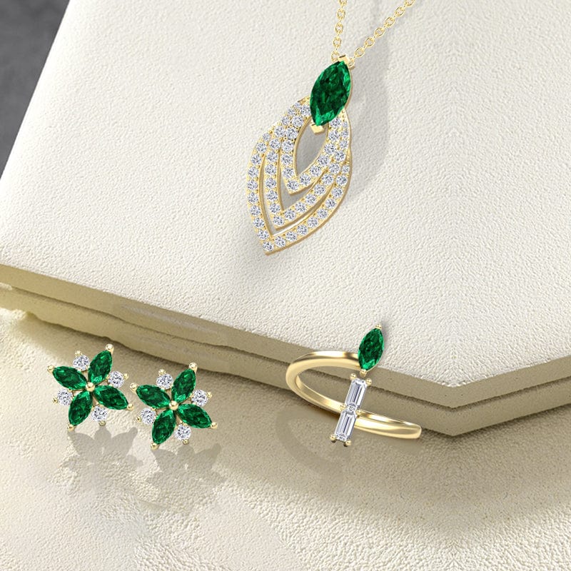 Gold jewelry set with green gemstones on a beige surface