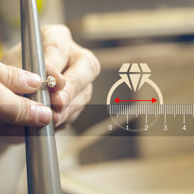 Hand holding a diamond ring next to a ruler for size measurement.