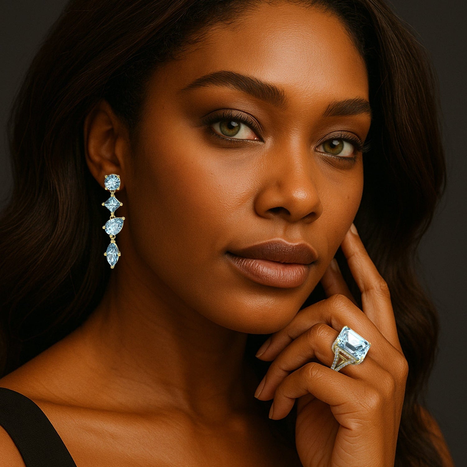 Aquamarine - March Birthstone Woman wearing blue stone earrings and ring against a dark background