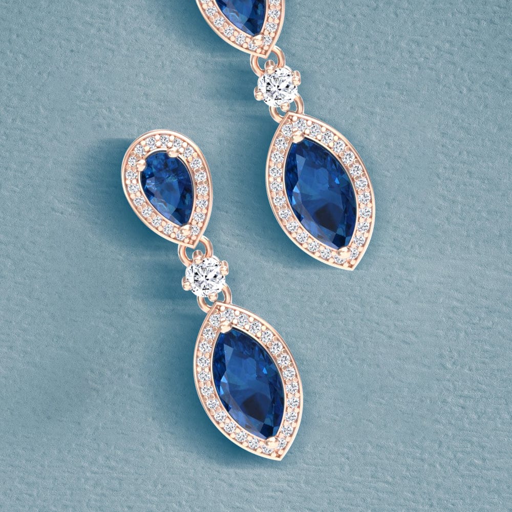 Rose gold earrings with blue topaz gemstones on a light blue background